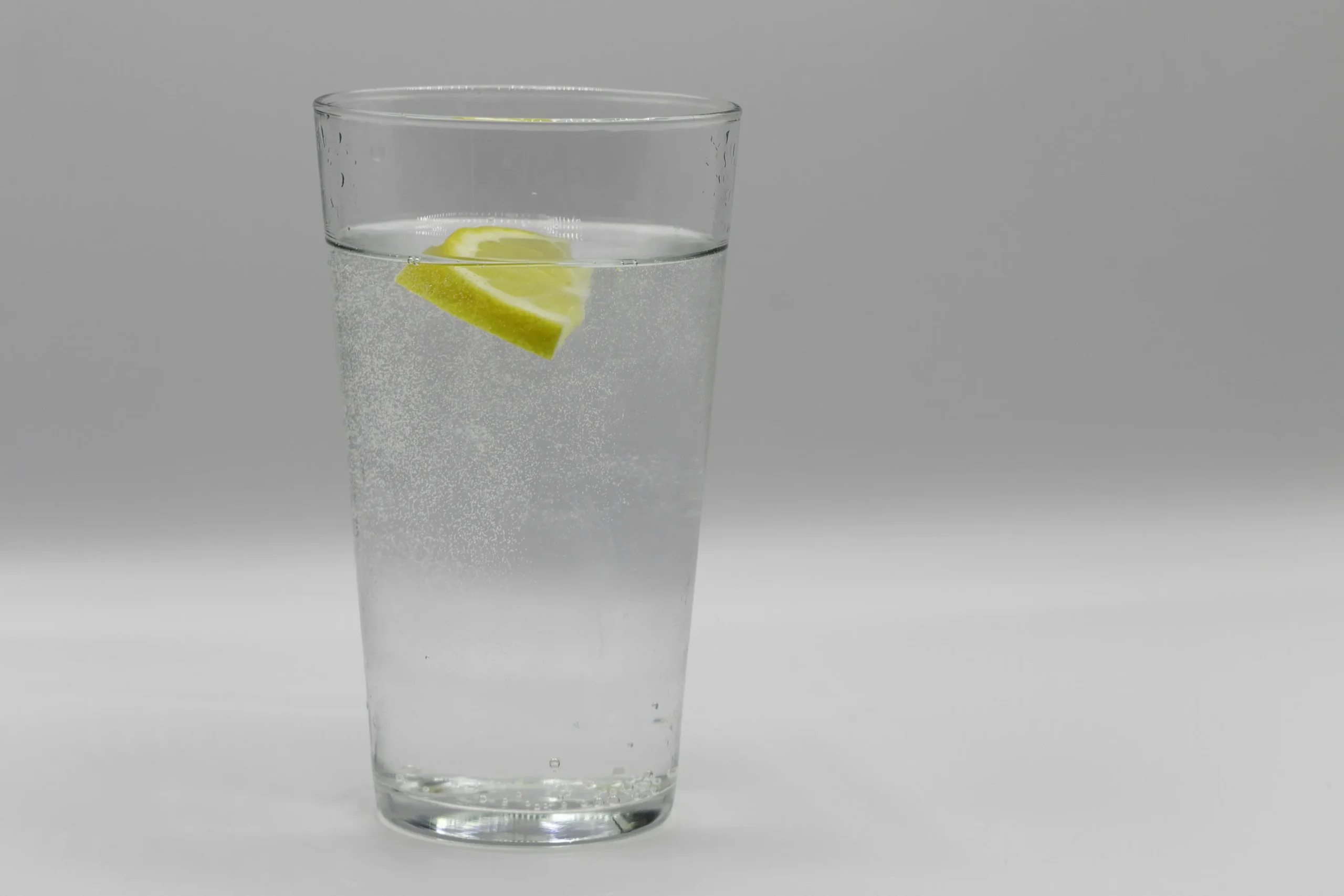 un bicchiere di vetro trasparente riempito di acqua dal erogatore Clik Soda con una fetta di limone dentro